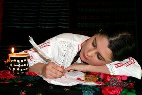 girl writes with pen in light of candle