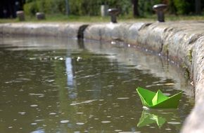 green paper boat on a pond in a park