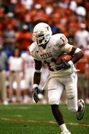 dark skin man in uniform running with ball on field, Football, Ball Carrier