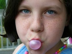 Freckled child Girl with bubble gum