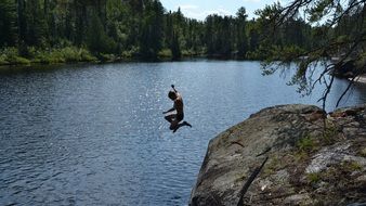 boy jumping off cliff in water