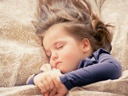 baby is sleeping and hugging quilt