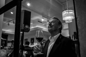 black and white photo of a man with a glass of wine in a restaurant