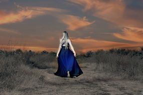 blonde in a long blue dress at sunset