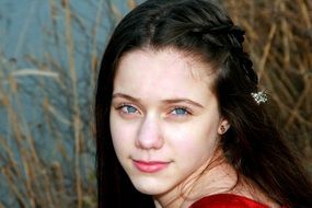 girl with blue eyes on a background of meadow plants