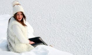 girl in white clothing sits on snow
