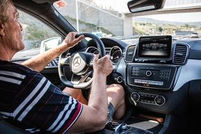 an elderly man driving a Mercedes