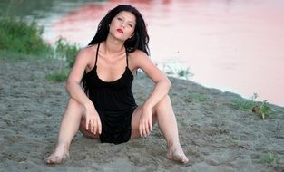 brunette sitting on the beach in the evening
