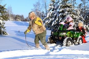 man pulls a quad bike in the snow