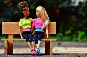 two dolls in a park on a bench