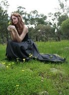 beautiful Girl in long black dress posing on meadow
