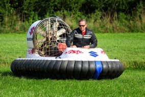 man is riding a hovercraft on a green lawn