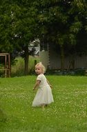 little girl plays on green grass