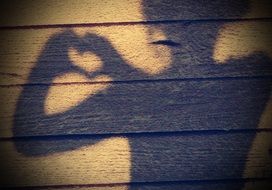 Child girl shadow with Hands in Heart Shape on wooden wall