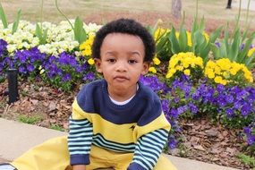 Child is sitting near the flower bed
