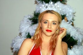 blonde in a red dress near the Christmas tree