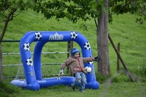 Child boy Playing Football on lawn at toy Goal