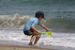 a child plays with a scoop by the sea