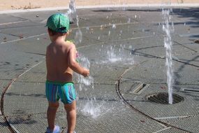 child in the fountain in summer