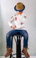a boy in a hat sits on a chair