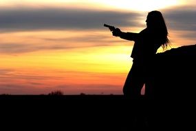 girl with pistol at sunset