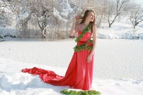 girl in a pink dress with green decorations in the snow