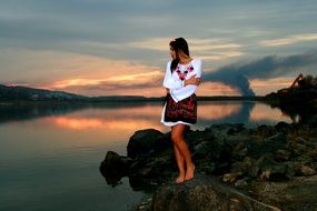 girl in traditional costume near the lake at sunset