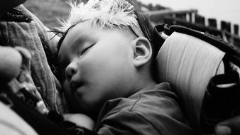 black and white photo of a baby sleeping in her motherâs arms