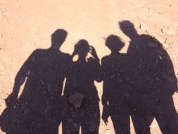 four black human shadows on the sand