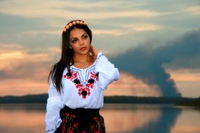 girl in traditional costume near the lake at dusk