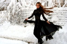 girl in a long black dress among the winter landscape