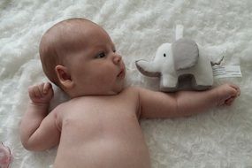 little baby lies on the bed with a toy