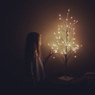 little girl on the background of a beautiful lamp with lights