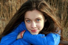 photo of a pretty girl in a blue jacket on a field background