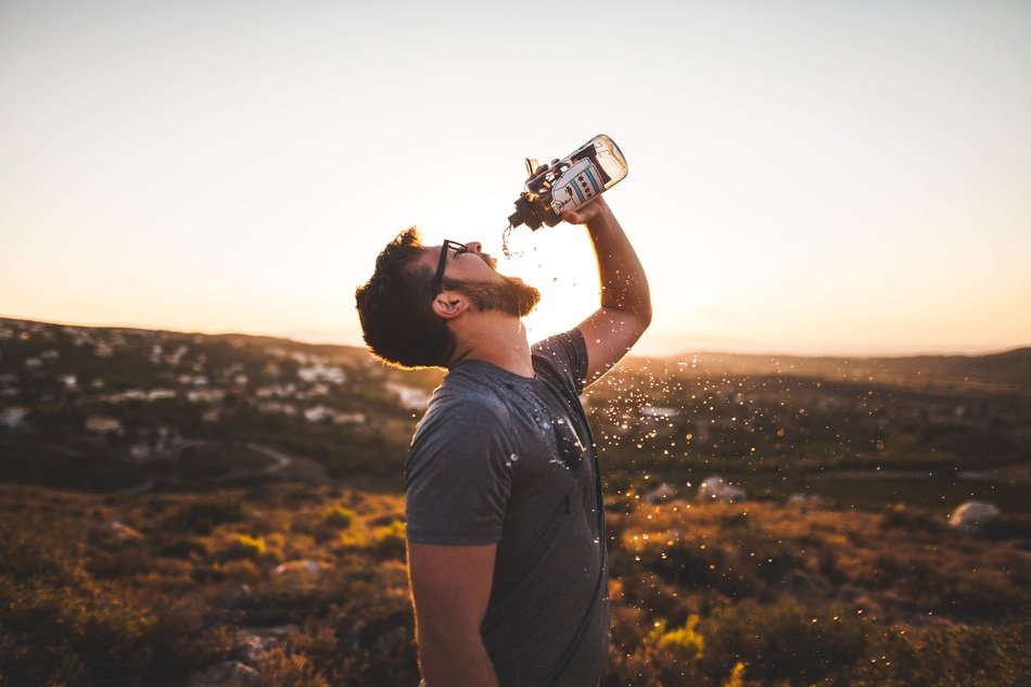 man drinking in the mountains