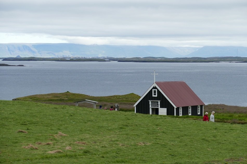 chapel on a green meadow near the water in iceland