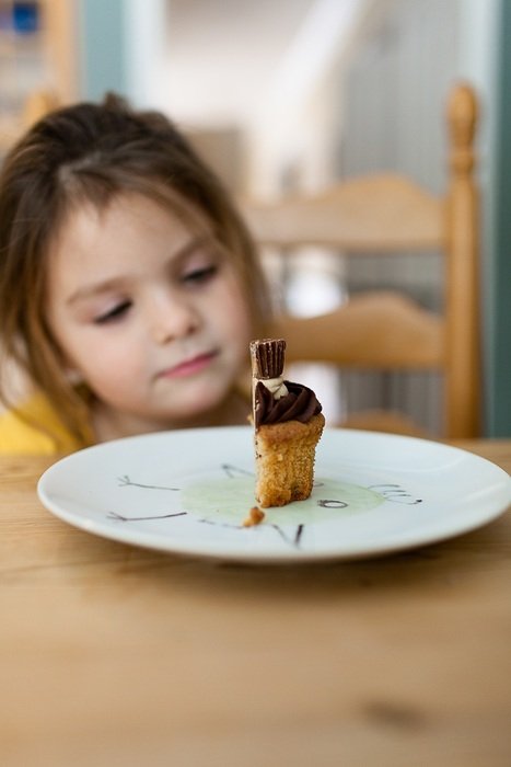 girl looks at half a muffin on a plate
