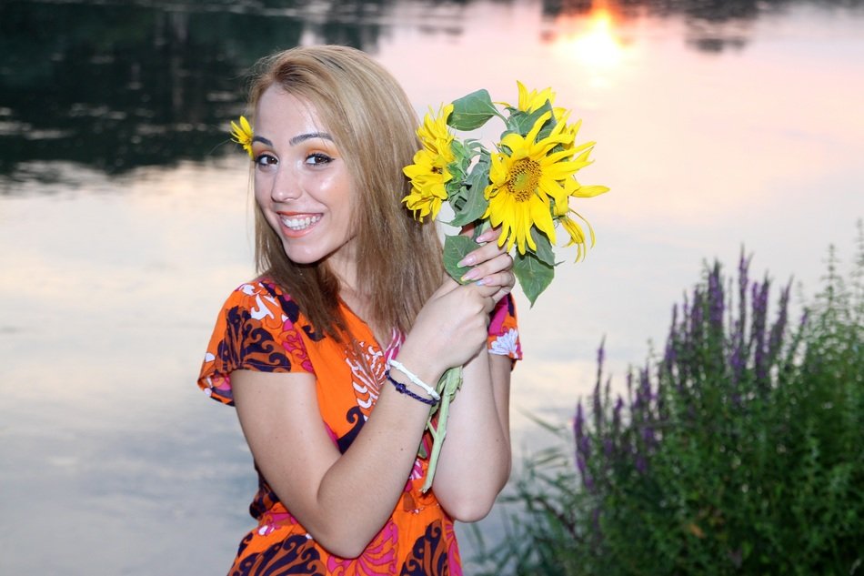 girl with sunflowers near the lake in the evening