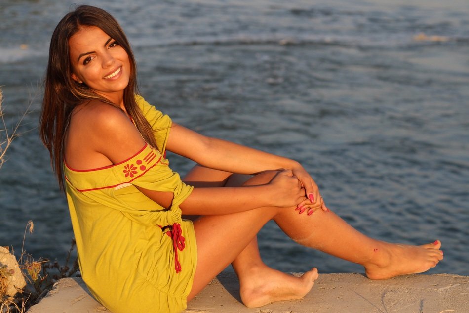 smiling girl in a yellow dress near the water