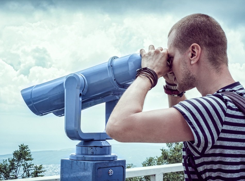 young man looking through binocular on Viewing Platform at sea