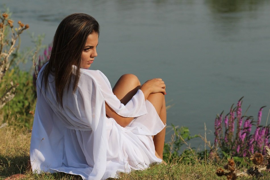 beautiful girl in white posing near the water