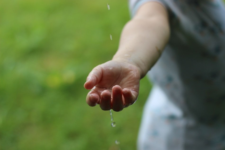 child hand under Drops Of Water outdoor