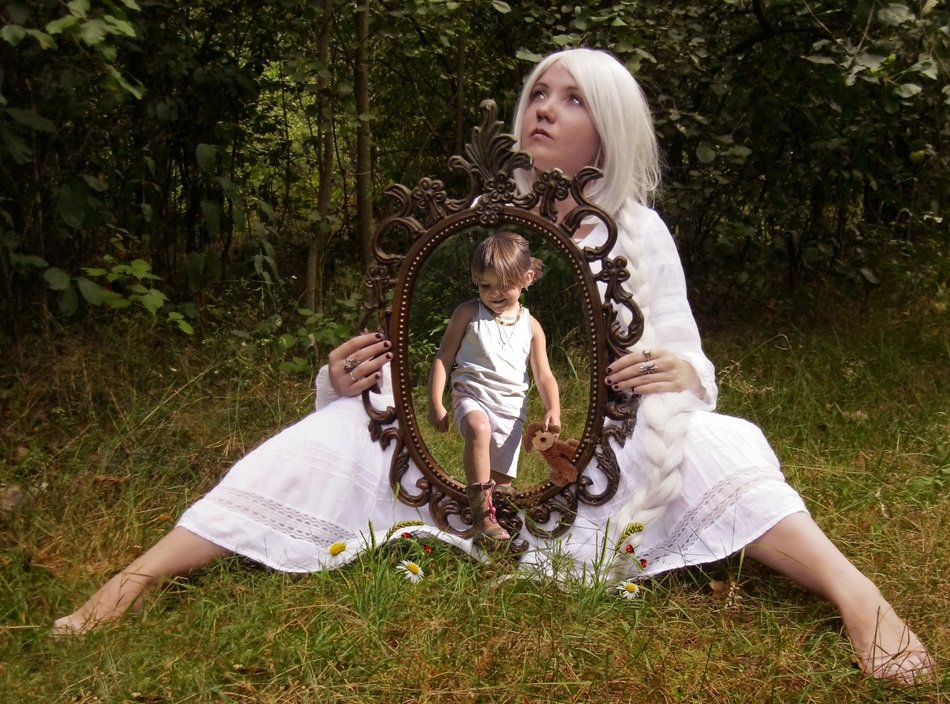 girl in a white dress with a mirror on the grass