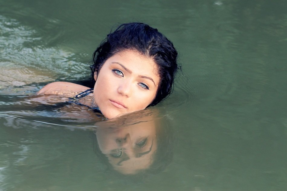 Portrait of brunette with blue eyes swimming in the water