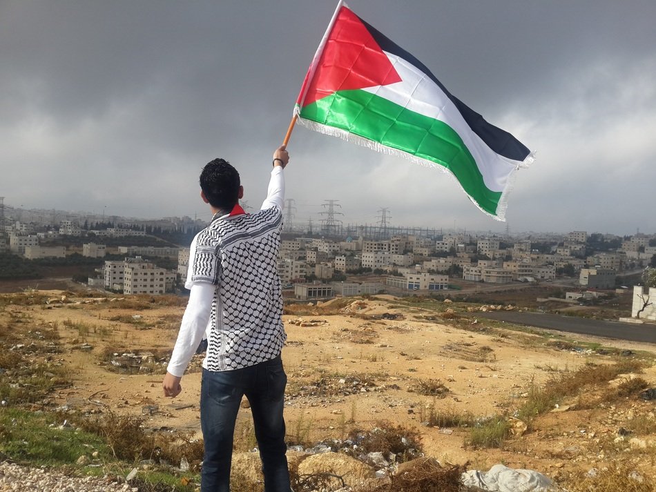 Arab Man Waving Flag at distant cityscape, Hejaz