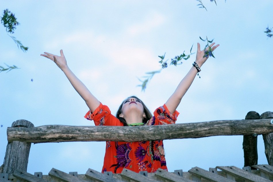 girl on a wooden bridge with hands up