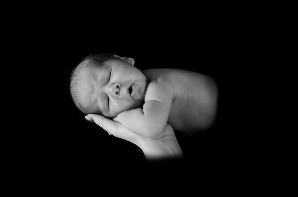 newborn on a hand on a black background