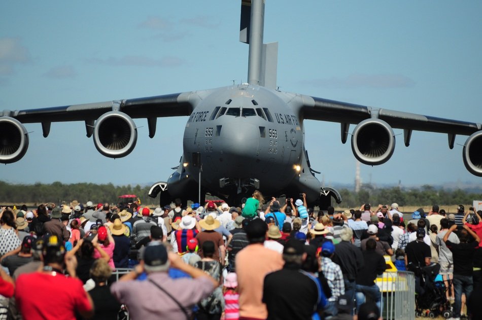 crowd of people near a military plane at an exhibition