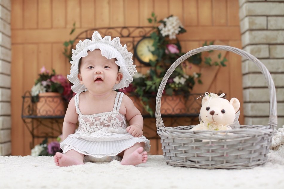 baby in white cap near the basket