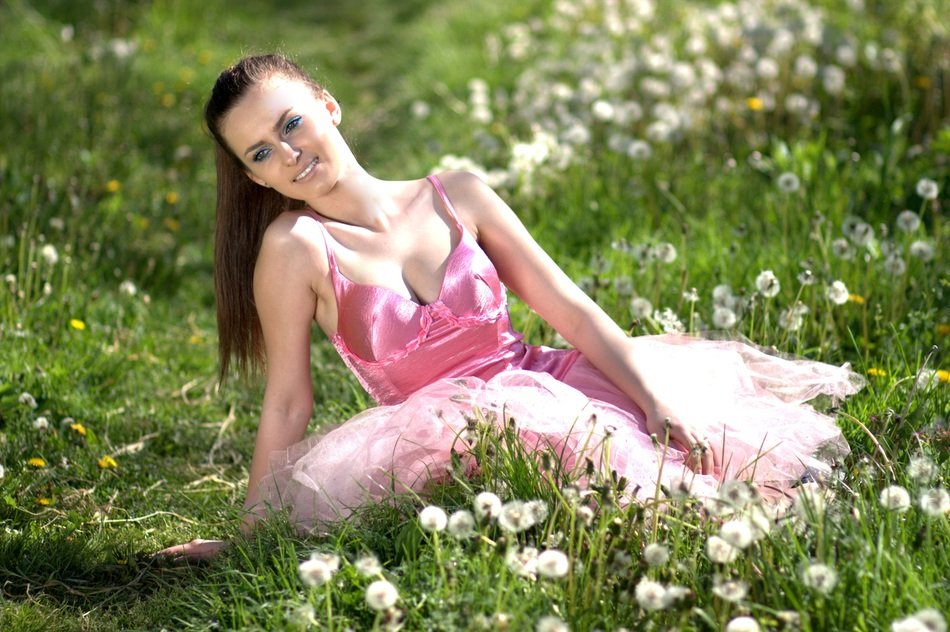 girl in pink on a meadow among dandelions